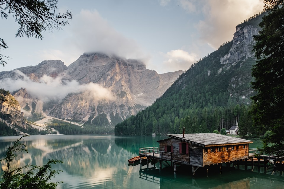 A lakeside cabin beneath forested mountain slopes